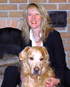 Tammie Ross is the woman with blond hair wearing a white shirt with black blazer. In front of her is a golden retriever.